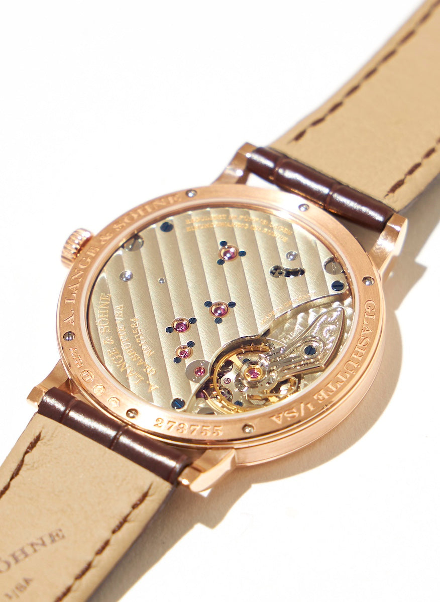 It features a plate that covers three-quarters of the movement, accented with rubies for the bearings and screws. The tiny screws are hand-fired and dyed blue by craftsmen.