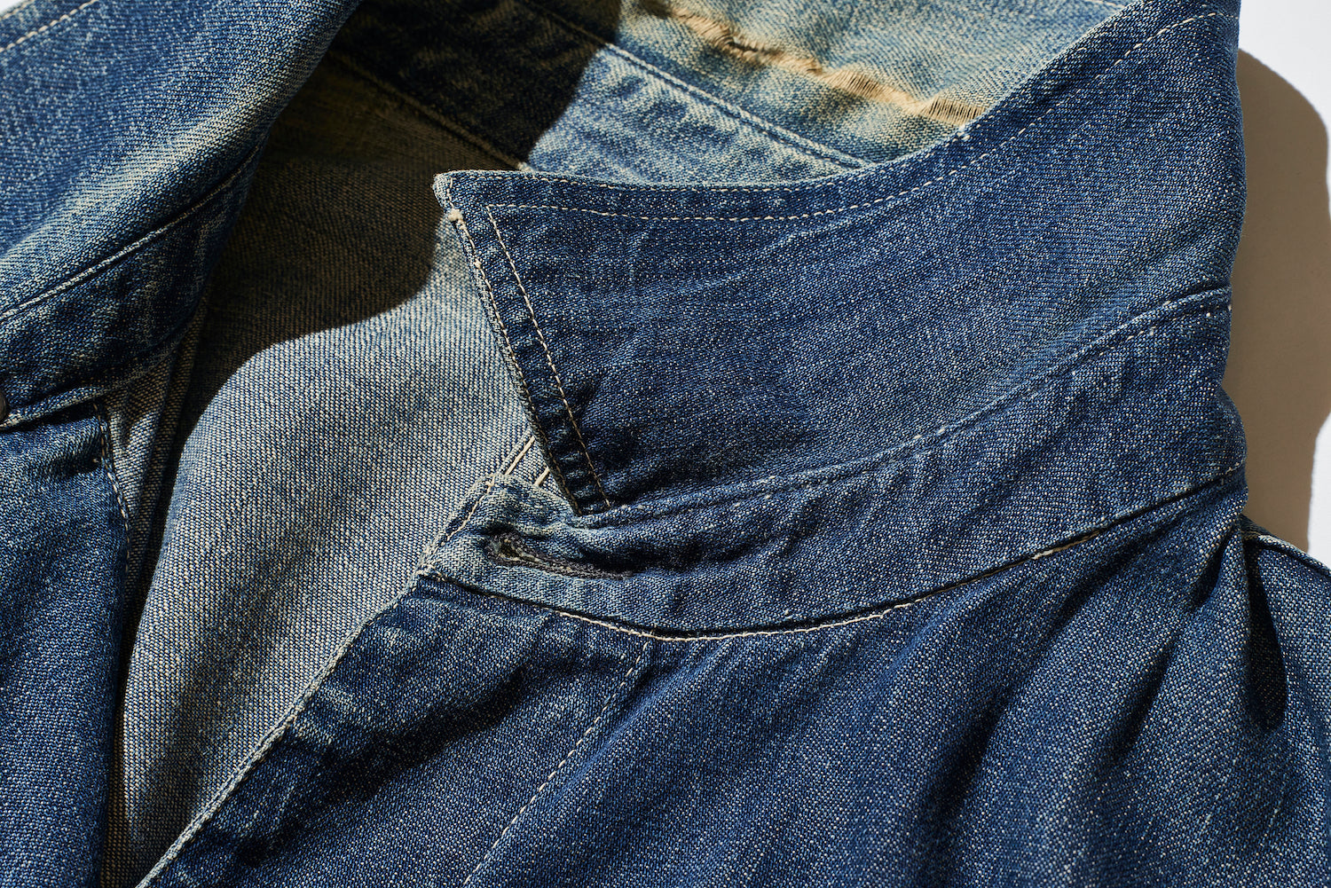 The collar and the body are not sewn directly together, but rather have a stand collar. This type of thin, curved stand collar, like that of a shirt, is not often seen on coveralls.