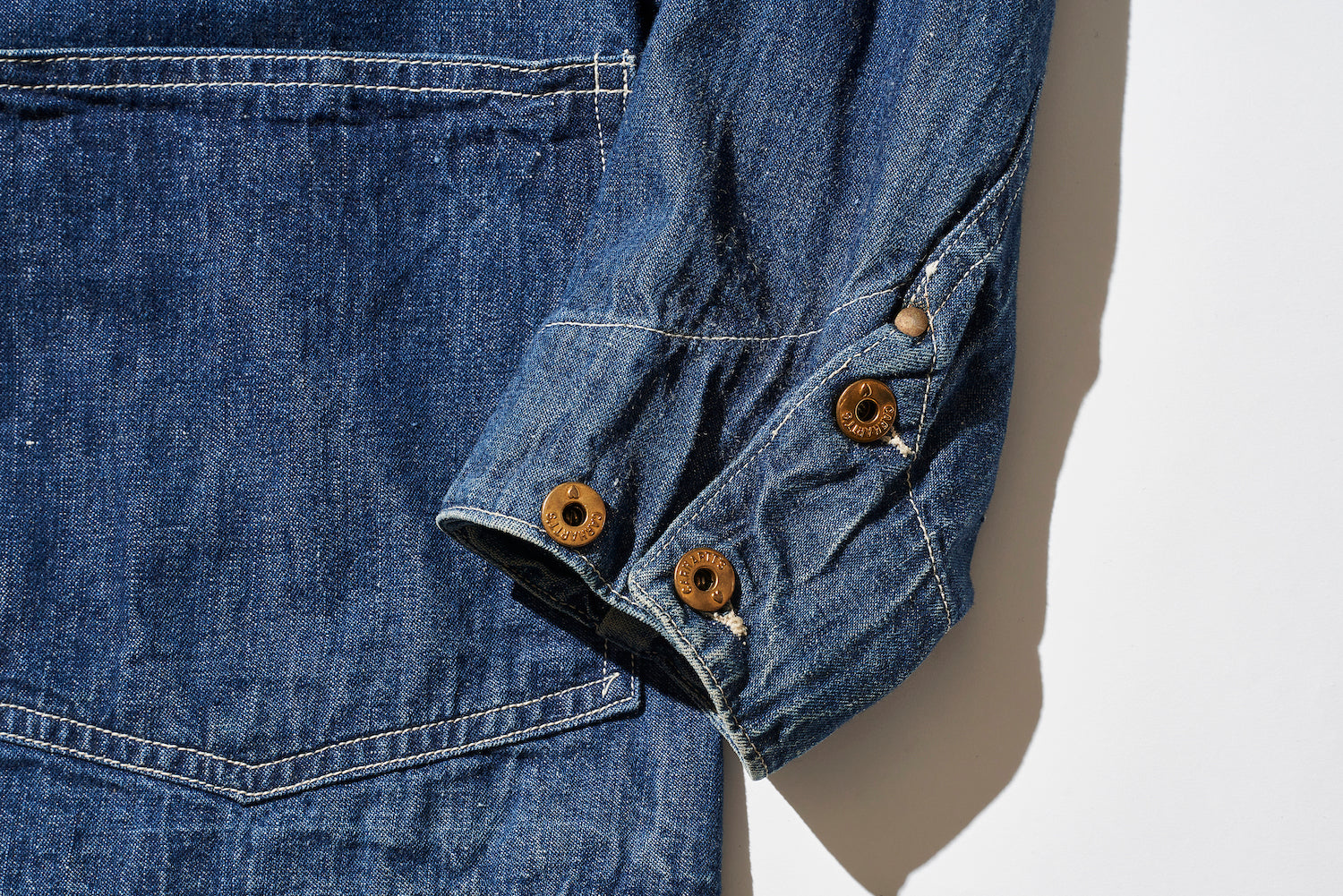 The cuffs are riveted, and the buttons are donut buttons, unlike the front.